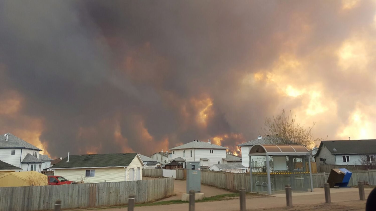 A wildfire burning behind a residential neighbourhood
