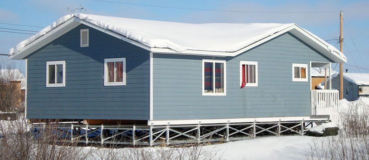 A home raised on a piled foundation above snow-covered ground