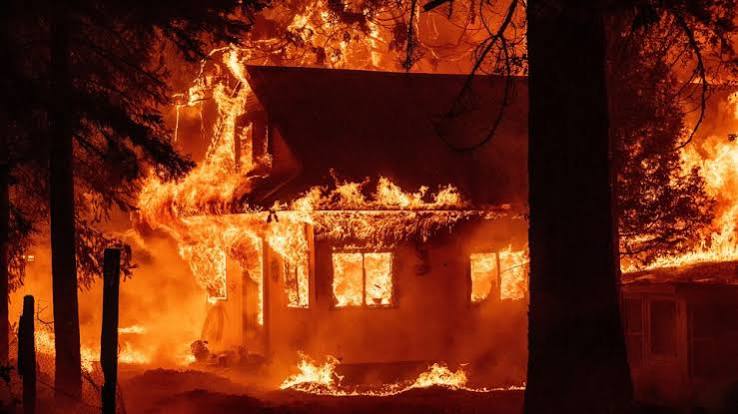 A house engulfed in wildfire flames at night